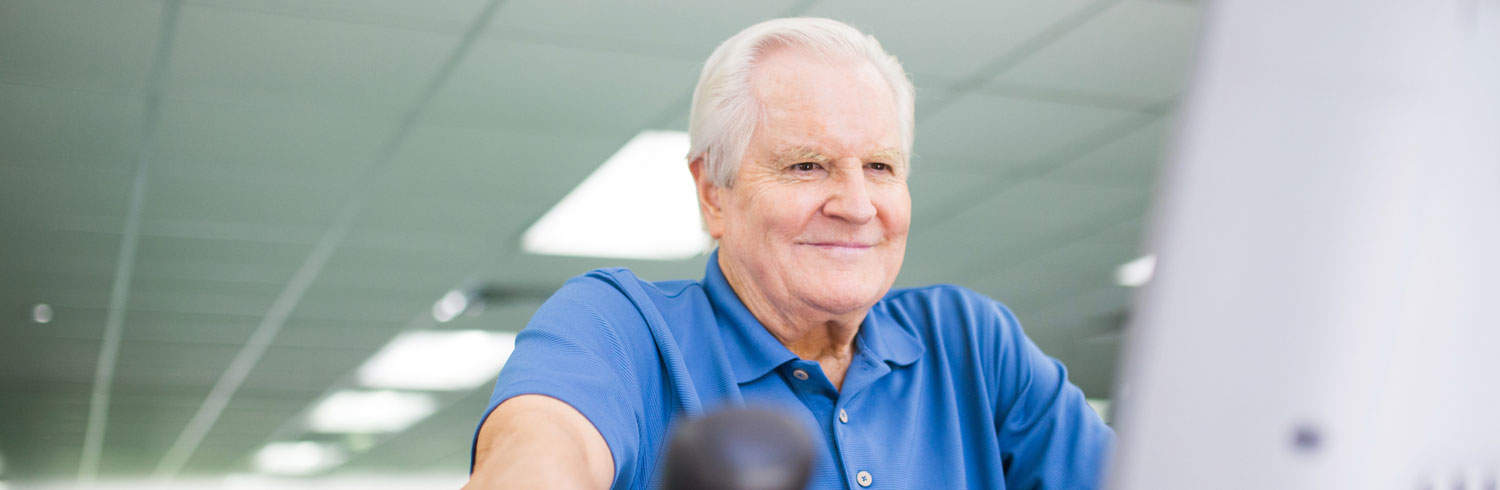 Smiling older man exercising in a bright gym.